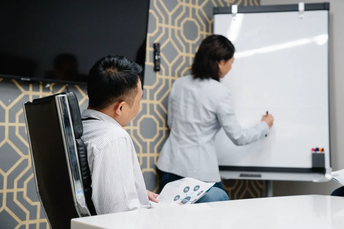 Reunião com quadro branco mostrando KPIs de atendimento