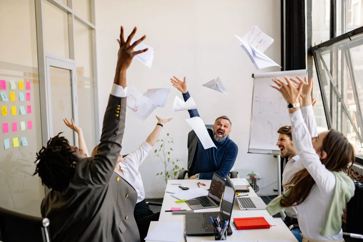 Equipe comemorando metas mensais em reunião no escritório