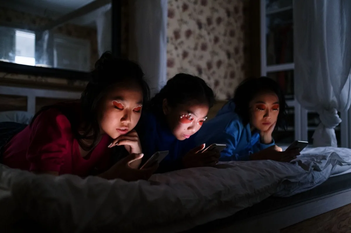 Adolescentes usando smartphones deitados à noite
