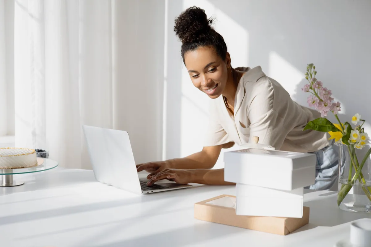 Vendedor sorridente revisando avaliações positivas no laptop