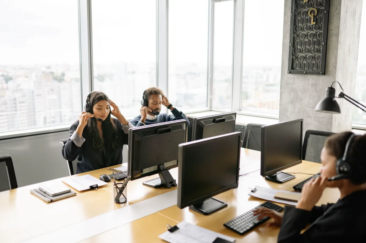 Equipe de atendimento ao cliente usando computadores e smartphones