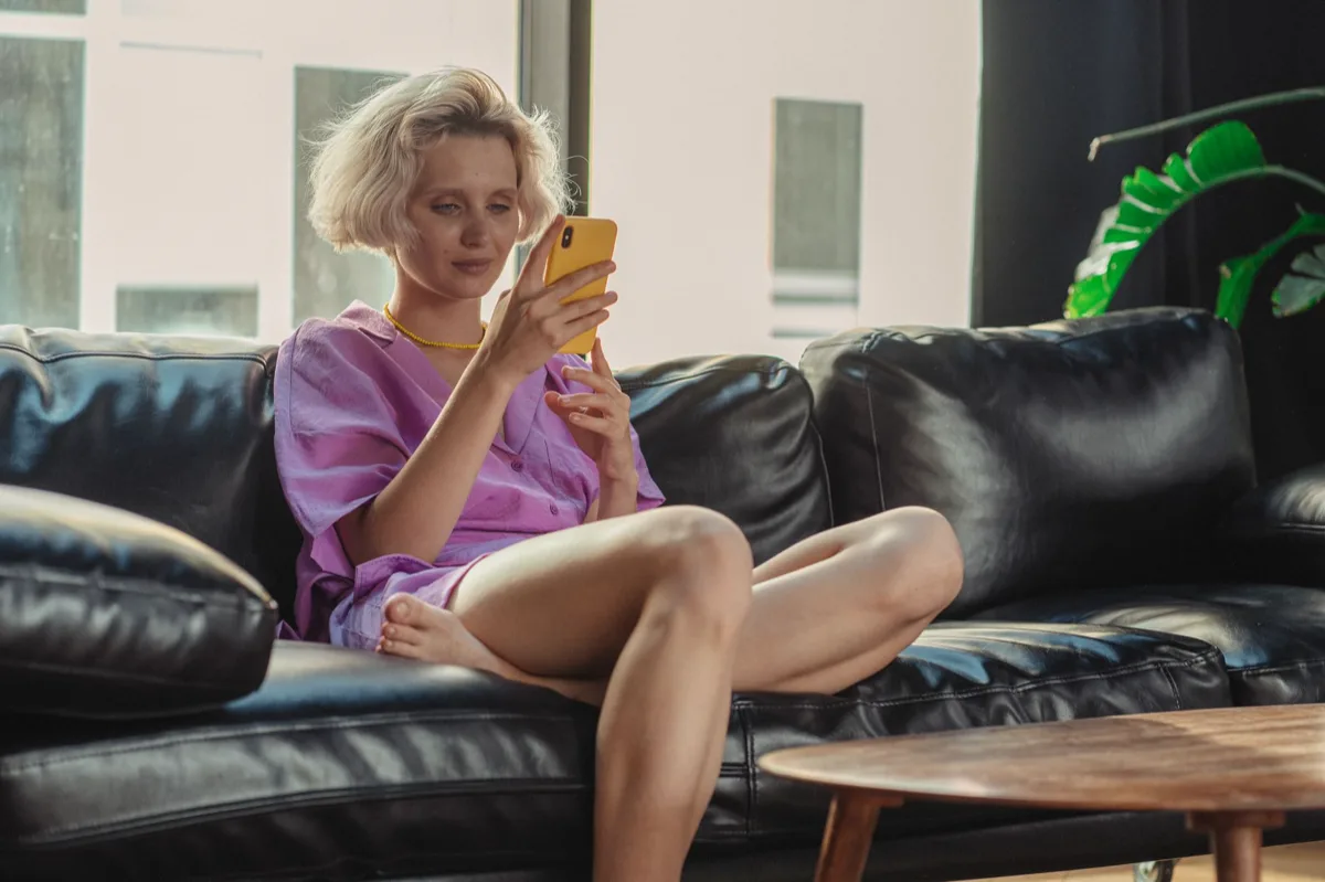 Mulher usando smartphone sentada no sofá